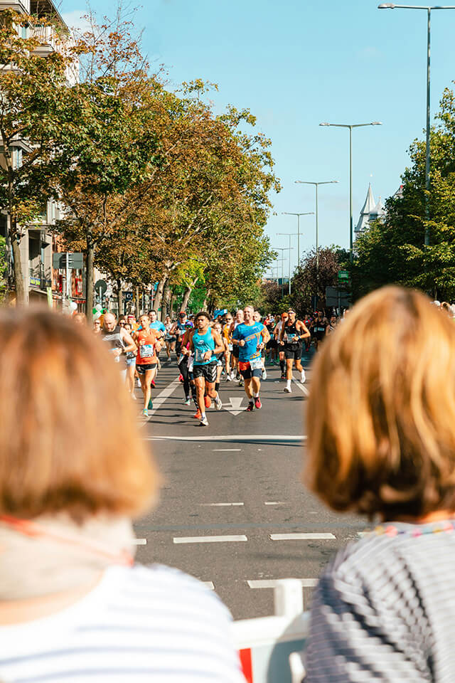 overlooking two ladies' shoulders, watching a group of people run a marathon